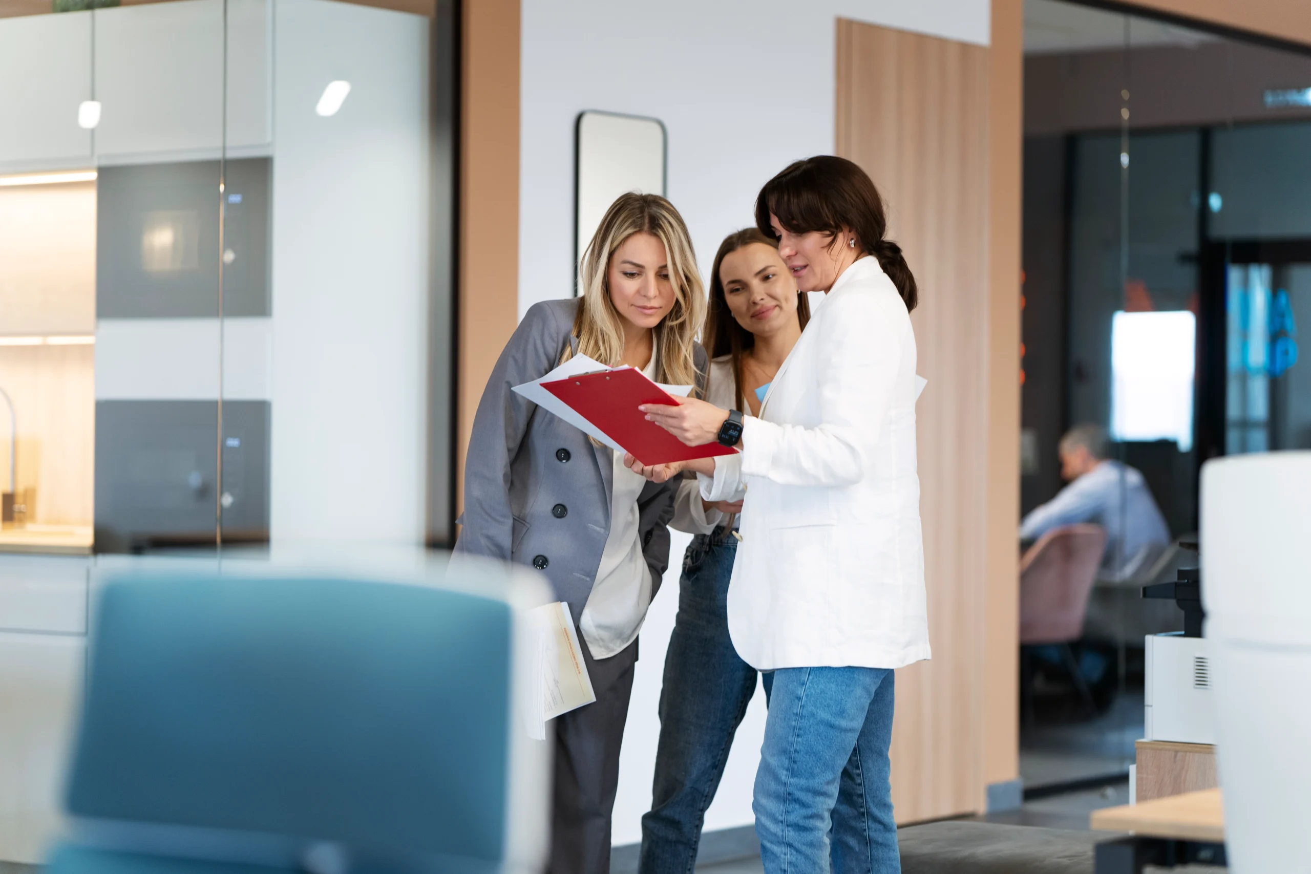A doctor reviewing paperwork with medical sales representatives in a clinic setting.