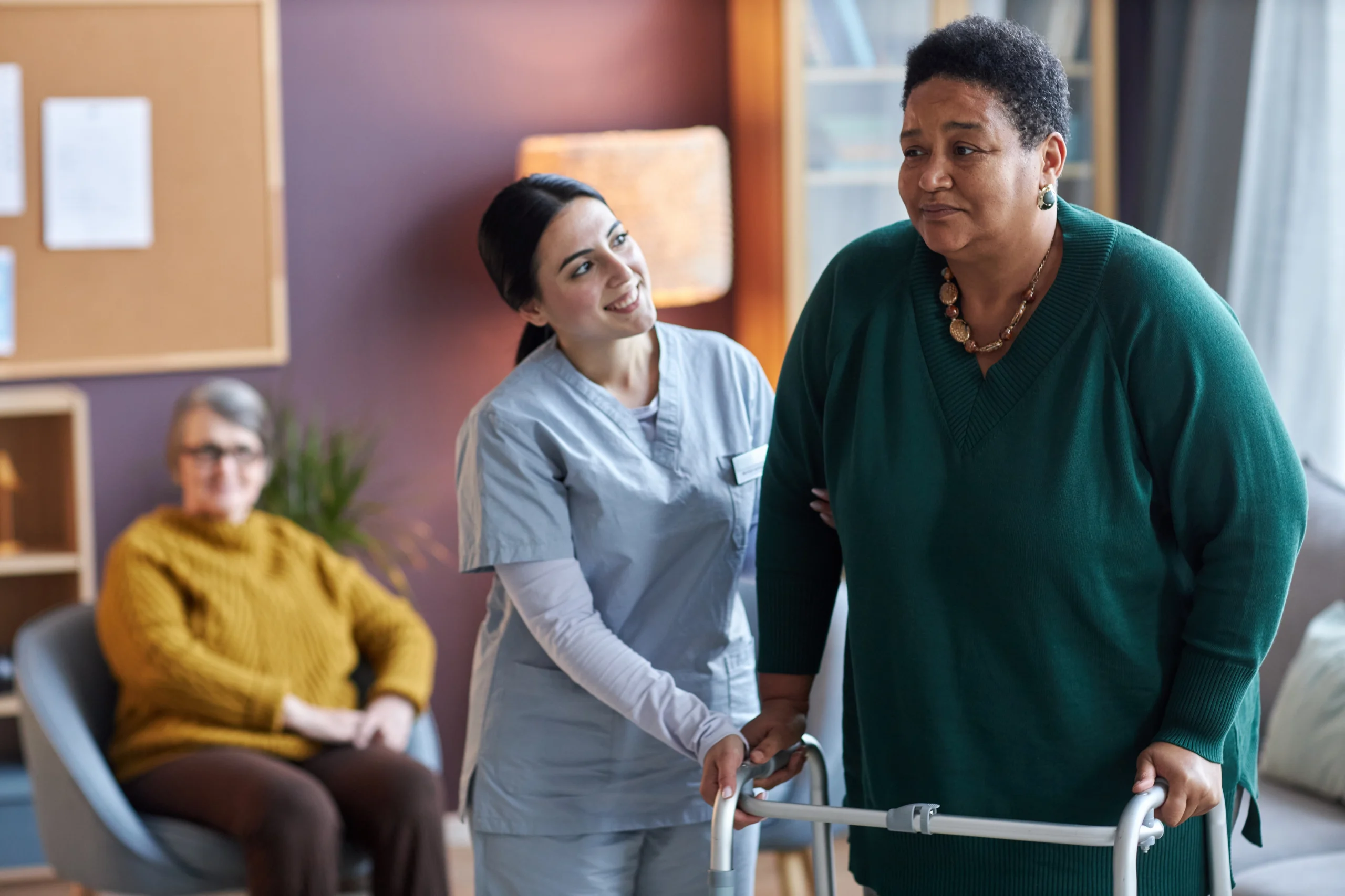 A hospice aide assisting a patient as they walk with a walker, ensuring stability and support.