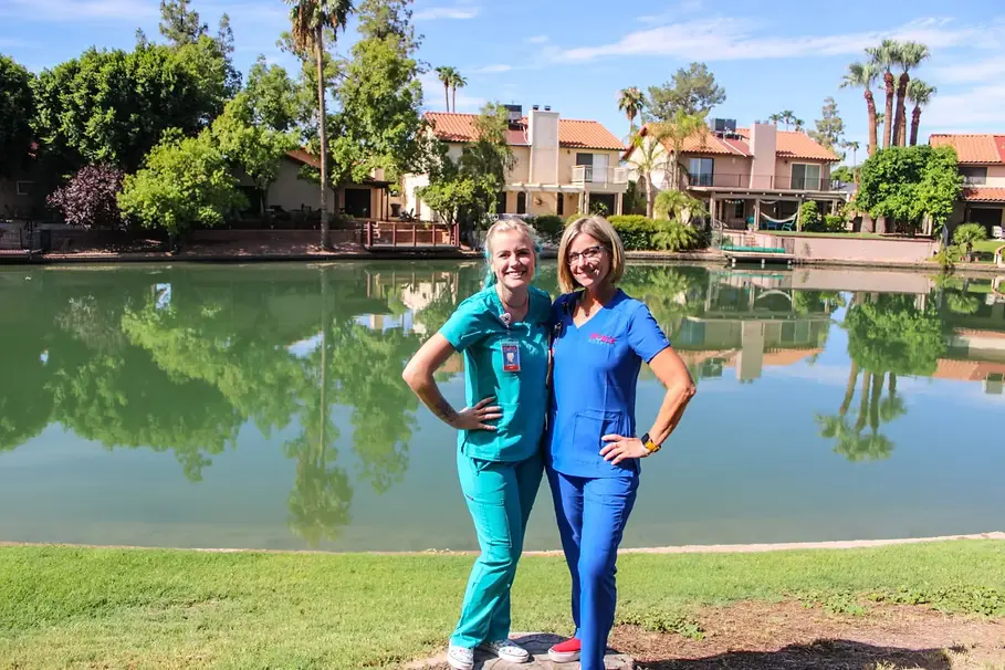 Two Noble Hospice aides standing together in front of a lake.