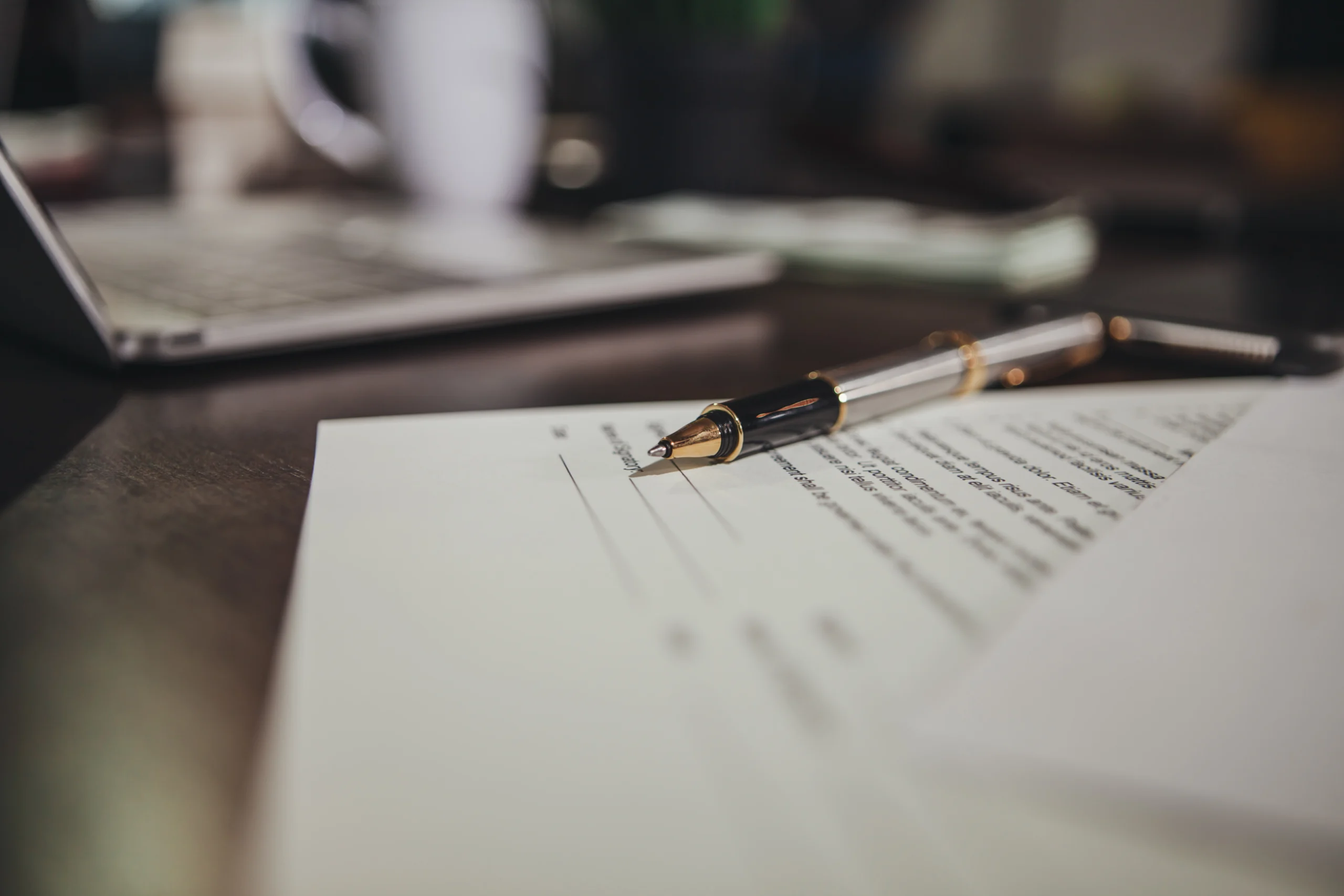 A pen resting on top of legal medical documents on a wooden desk.